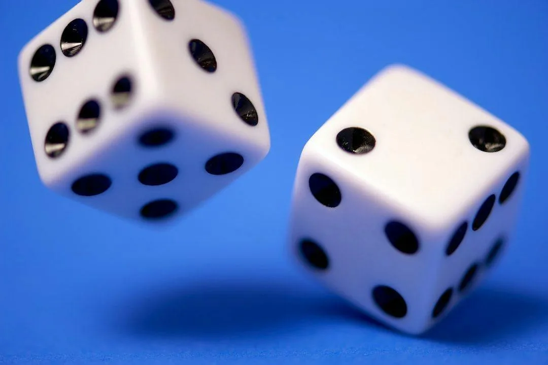 Two white dice tumbling against a blue background
